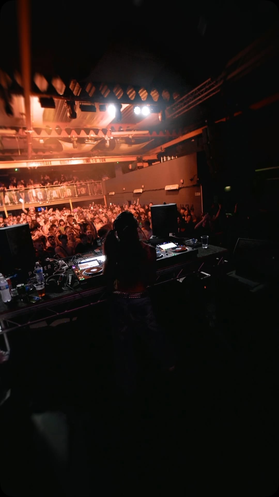 Behind the decks facing a packed floor